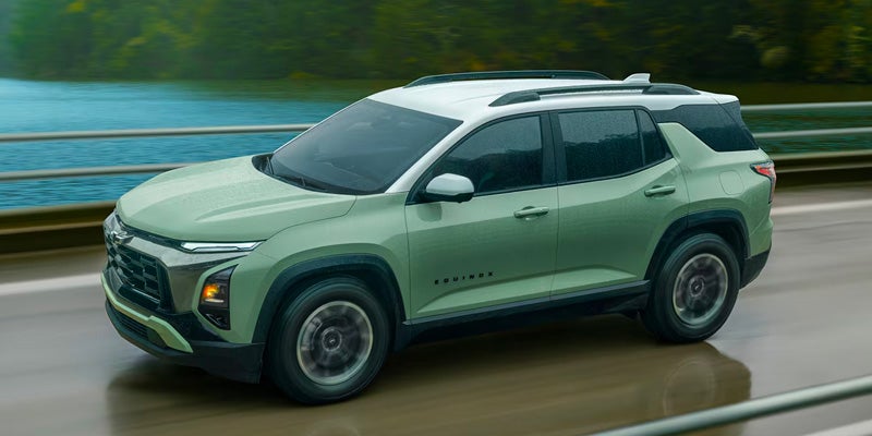 Light green Chevrolet SUV driving on a road beside a lake